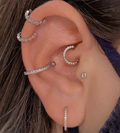 a woman wearing three different ear piercings on her left side, and one behind the ear