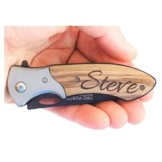 a hand holding a small knife with the word store engraved on it's blade