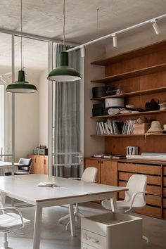 an office with wooden shelves and white chairs, two green pendant lights hanging from the ceiling