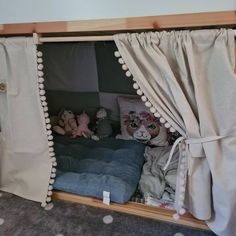 a doll house with stuffed animals in it and curtains on the window sill above