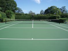 a tennis court with two people on it and trees in the backgrouds