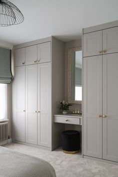 a bedroom with white cabinets and a large mirror