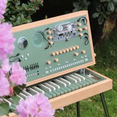 an electronic organ sitting on top of a wooden table next to purple flowers and greenery