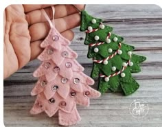 two handmade christmas trees are being held by someone's hands on a wooden table