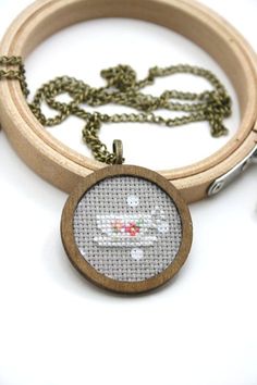 a cross stitch keychain with a wooden ring around it