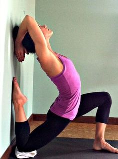 a woman is doing yoga in front of a wall