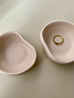 two white bowls with gold rings in them