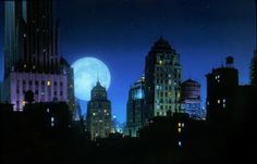 the full moon shines brightly in the night sky over some buildings and skyscrapers