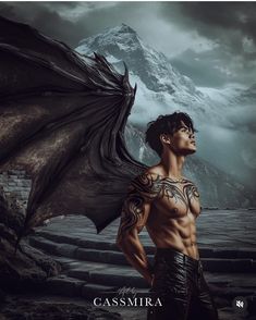 a man with tattoos standing in front of a mountain and holding a dragon's wings