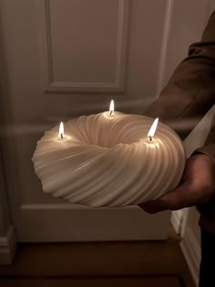 a person holding a candle in their hand with two lit candles on the inside of it