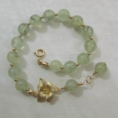 This floral bracelet is interestingly styled, and will go with casual wardrobe and elegant formal attire. The round natural stones of light green rutilated tourmaline quartz measure approximately 8.5 mm in diameter, semi-transparent with some of the typical streaky dark green moss inclusions and mottles. They are organic, somewhat rustic-looking stones, with some very slight hollows/dents, stone veins and spots. Each of these natural stones is always grained and mottled differently, therefore ea Tourmaline Quartz, Floral Bracelet, Flower Leaf, Hibiscus Flower, Beading Wire, Leaf Charms, Quartz Bracelet, Small Pendant, Formal Attire