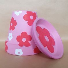 two pink cups with red and white flowers on them sitting next to each other in front of a beige background