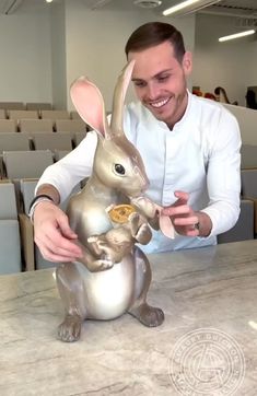 a man sitting at a table with a statue of a rabbit