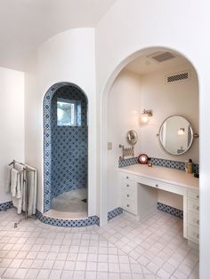 a large bathroom with blue and white tiles on the walls, an arched doorway to another room