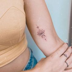 a woman's arm with a small flower tattoo on the left side of her right arm