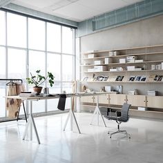 an office space with large windows and shelves on the wall, along with chairs and desks