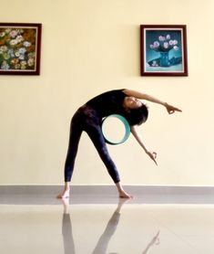 a woman holding a frisbee in her right hand while standing on the floor