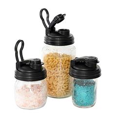 three jars filled with different types of cereal in each jar and one has a black lid