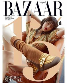 a woman sitting on top of a brown chair next to a magazine cover with her legs crossed