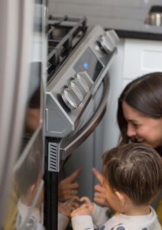 a woman and two children looking at an oven