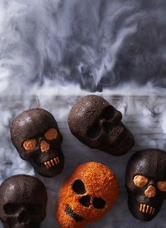 there are five skulls that have been made out of chocolate and orange powdered sugar