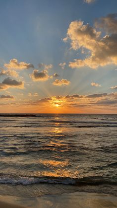 the sun is setting over the ocean with clouds in the sky and waves on the beach