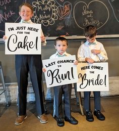 three young boys holding up signs in front of a chalkboard that says i'm just here for the cake