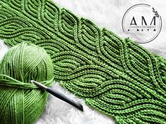 a ball of green yarn next to a knitting needle and crochet hook on white furnishing