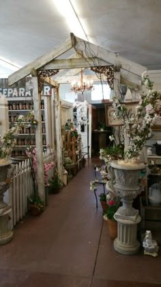 the inside of a flower shop with lots of potted plants and vases on display