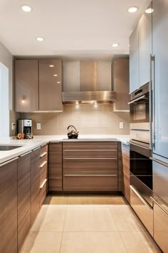 a modern kitchen with stainless steel appliances and wood cabinetry, along with floor to ceiling windows