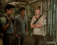 three young men standing next to each other in front of bamboo walls and tree branches