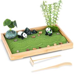 a bamboo tray with two pandas and rocks in the grass next to a potted plant