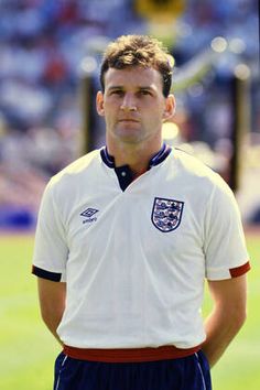 a man standing on top of a soccer field wearing a white shirt and blue shorts