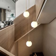 three lights hanging from the side of a staircase next to a table and chairs in a living room