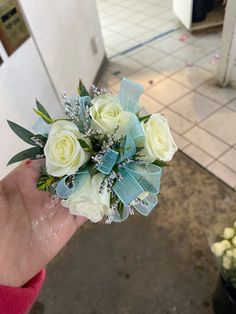 a hand holding a bouquet of white roses and greenery in it's palm