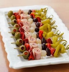 several skewered vegetables are arranged on a white platter