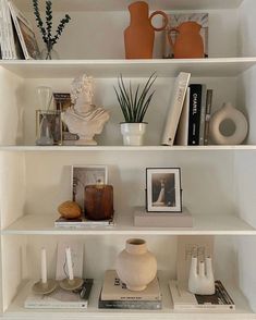 a white shelf filled with books and vases