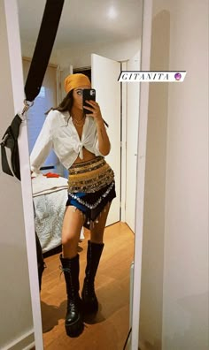 a woman is taking a selfie in the mirror while wearing boots and a hat