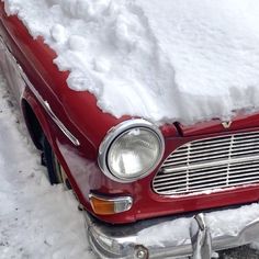 an old red car is covered in snow