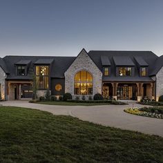 a large house lit up at night with lights on the windows and grass in front