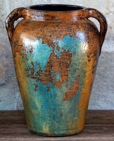 an old vase is sitting on a wooden table