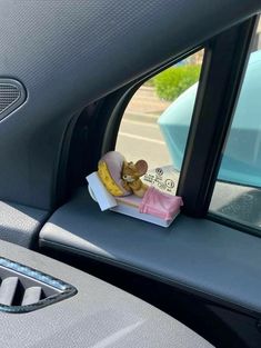 a stuffed animal sitting in the passenger seat of a car next to a package of food