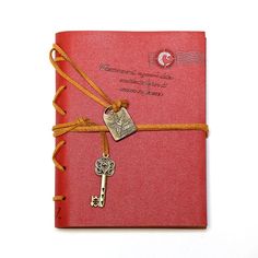 a red book with a key tied to it's side and a ribbon around the cover