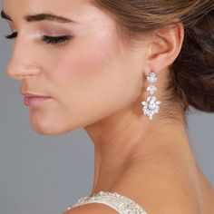 a woman in a white dress wearing earrings with flowers on it's back side