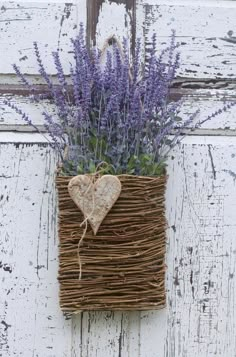 a heart shaped planter hanging on the side of a white door with purple flowers in it