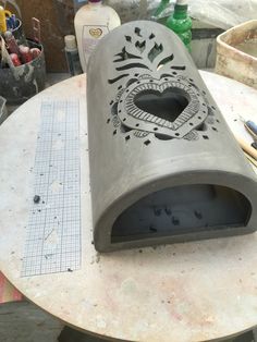 a heart shaped object sitting on top of a table next to some paint and pencils