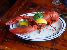 a lobster on a plate with lemon and parsley garnished with sauces