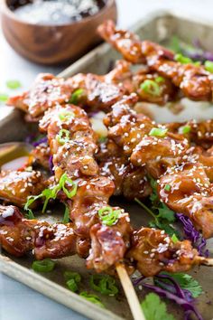 chicken skewers with sauce and greens on a tray