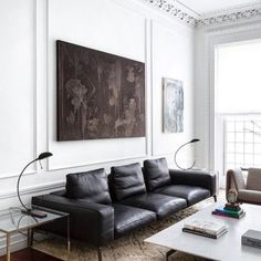 a living room filled with furniture and a large painting hanging on the wall above it