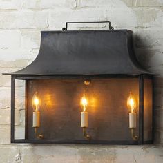 a wall mounted light with four lit candles on the front and back of it,